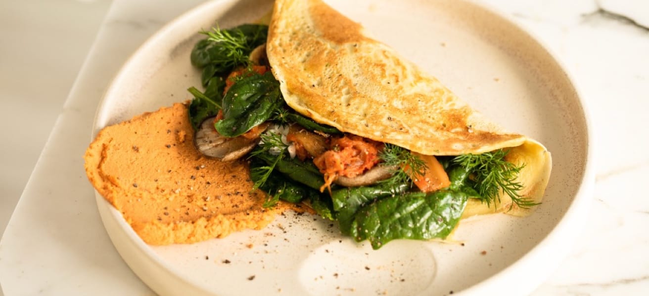 A close-up view of a freshly cooked omelette on a white plate.